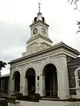 SYMMETRICAL PLAN BELOW A RIDGED AND HIPPED ROOF WITH A CENTRAL, 3 ARCHED, DOUBLE VOLUME ENTRANCE PORCH WITH AN ORNATE CLOCK TOWER ABOVE IT. FENESTRATION MAKES USE OF 4 PANE SASH WINDOWS WITH RAISED PLASTER SURROUNDS AND ARCHED FANLIGHTS. THE CENTRAL ENT This building was first occupied in 1877 and accommodated various Government departments. The building has an imposing clock tower with a memorial clock, which was installed in memory of John Brownlee, first missionary and founder of King William's Town.
Type of site: Courthouse.
Current use: Magistrate's Court.