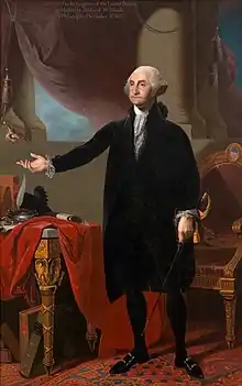 Washington standing up, dressed in a black velvet suit with an outstretched hand held up in an oratorical manner.