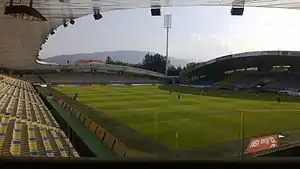 An empty football stadium on a sunny day with mountains in the background.