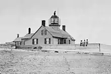 The original lighthouse and keeper's house.  Note the three small children seated in front.