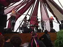 Lulu and the Lampshades, Bestival 2010; left to right (without the "Lampshades"): Dan Blackett (drums, hidden),Heloise Tunstall-Behrens (violine),Luisa Gerstein (ukulele),Jemma Freeman (electric guitar)