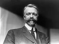 A black-and-white of a man with a mustache wearing a suit and a tie