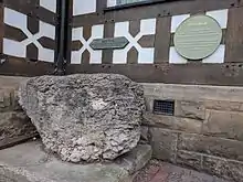 The stone is against the half-timbered wall of Exmewe Hall, on St. Peter's Square, Ruthin.