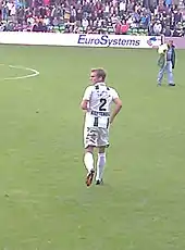 Back view of a fair-haired white man wearing sports kit on a field