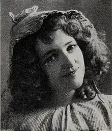 Head and shoulders of a young woman with mid-length curly hair