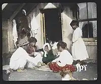 Māori woman and children playing cards on doorstep of their home in Whakarewarewa, 1895