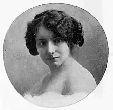 A white woman with short dark wavy hair in a circle frame.