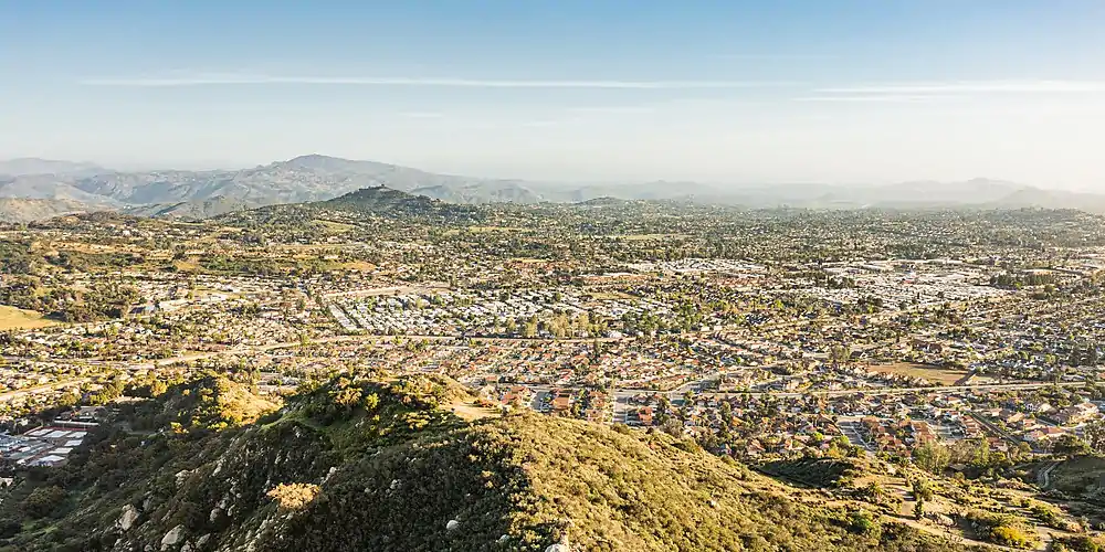 Looking south across Escondido from over Dixon Lake. At the very left in the distance is the peak of El Cajon Mountain, with Mount Woodson looming closer at left of center. Farther right is the flattened rise of Twin Peaks, with Black Mountain at right side of the frame.