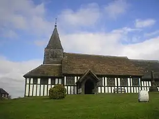 A timber-framed church with a small tower and spirelet