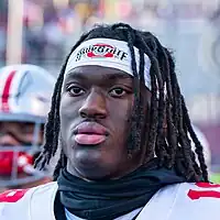 Close-up photo of a man with braided hair in a football uniform.