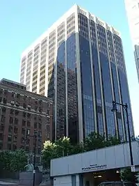 Ground-level view of a 20-story building with prominent black windows and a white, concrete facade