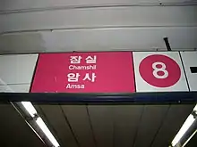 An overhead sign in rose and white with a big number 8 and the words Chamshil and Amsa in hangul and Latin script.