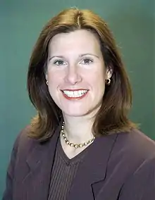 A middle-aged female smiles, while wearing a dark colored jacket