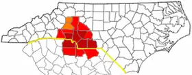 Counties most commonly associated with Metrolina are in dark red, counties often included are light red, and counties sometimes included are in orange. The NC/SC state line is shown in yellow.