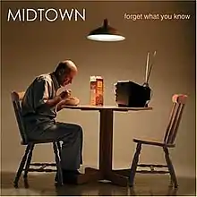 A man sitting at a table eating cereal and watching TV