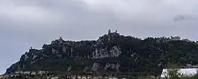 Mountain with some rocks and three fortresses on top.