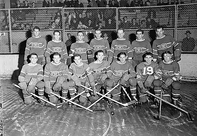 1942 Montreal Canadiens posing for photo on rink. First row of seven players kneeling and second row of seven players standing behind.