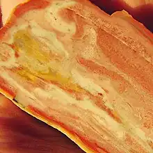 A slice of mozarkite with the face showing a swirling pattern of cream, pinks and yellows.