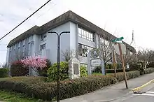 A three-story building painted light blue with a brown roof, seen from a nearby street.