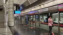 The station platform is separated from an incoming train by the platform screen doors.