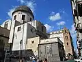 View from left flank, showing dome, Capella Pontano left of the facade, and the brick bell tower to right of façade