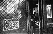 The lieutenant in charge of security checks suspicious car license plates outside a Nazi bookshop in Cleveland, Ohio.