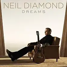 Picture of a man lounging in a comfort chair with a guitar by his side