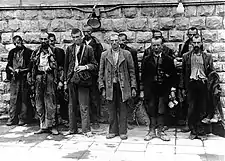 Disheveled men standing against a wall