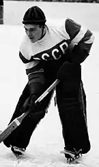 An ice hockey goaltender with small pads and no helmet leans over his stick