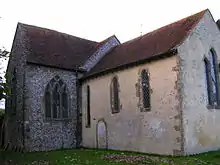 Two parts of a church at right-angles to each other, one rendered, one flint, both tiled