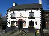 A rendered two-storey public house with steps leading up to a central doorway