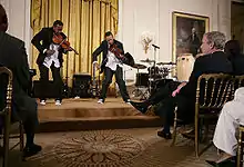 President George W. Bush and guests watch violinists Tourie and Damien Escobar, as they perform Friday, June 22, 2007 in the East Room of the White House, in celebration of Black Music Month.