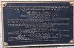 A history plaque, mounted on the Burd Street side of the bank building located on South Broadway & Burd Street in Nyack. The inscription says "Nay-ACK, which being translated means THE FISHING PLACE...The First Settlement ...Rockland County, NY...took place in 1675."