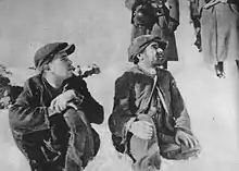 Two men in caps, sitting in the snow