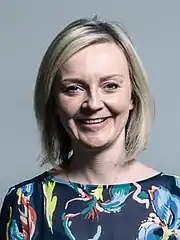 Truss smiling in front of a light grey background.