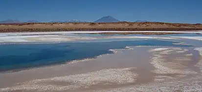 Photo of a lake below a scarp, with a mountain rising behind