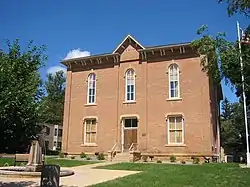 A boxy, two-story brick building fronting a small plaza