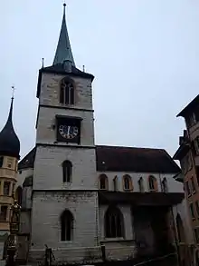 A grey stone Gothic spire rises above the Old City of Bern