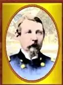 Head of a white man with brown hair, mustache, and beard, wearing a blue military jacket with two columns of gold buttons down the chest. The portrait is in a golden oval-shaped frame.