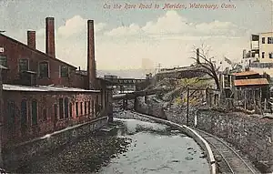 A postcard showing a railroad track next to a winding river in an urban industrial area