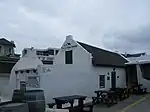 This cottage which for many years was the property of the Stadler family, is a typical example of the simpler form of vernacular architectural style found on the coastal areas of the Western Cape. The periodic additions, the plain side gables and the ove Type of site: House.