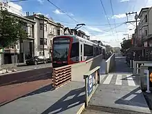 A red-and-silver light rail train at a surface stop in the center of a city street