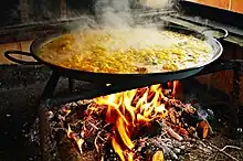 Paella being cooked on a wood fire in the middle of the road