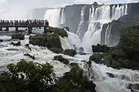 A set of waterfalls, with people viewing from a bridge