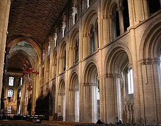 Peterborough Cathedral, the three-stage nave 1155–1175 has piers of ovoid section with attached shafts.  While the forms are typically Norman, the length is greater than found in Normandy. The wooden ceiling is original.