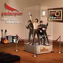 Four people–one holding a microphone, two holding a guitar, one holding drumsticks–exhibited in a display case