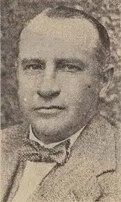 A man wearing a jacket, white shirt, and dotted bow-tie.