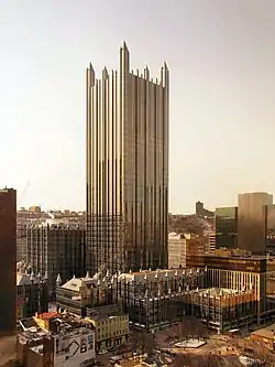  an all glass building with no other tall buildings around it. It is topped off by a glass spire on each corner and is surrounded by much shorter but similarly Gothic glass buildings.