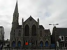 Stone church with blue stained glass windows and a steeple.