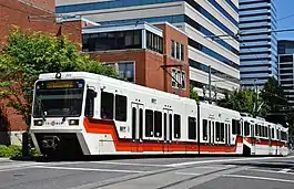 A MAX train composed of a low-floor car and a high-floor car southbound on 5th Avenue at Mill Street in downtown Portland